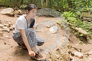 Asian woman tie her shoe in the forest