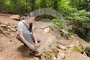 Asian woman tie her shoe in the forest