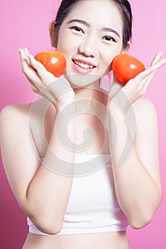 Asian woman with tomato concept. She smiling and holding tomato. Beauty face and natural makeup. Isolated over pink background.
