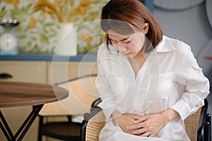 An Asian woman is touching her stomach due to suffering from stomach aches and undesired symptoms