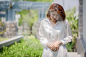 An Asian woman is touching her stomach due to suffering from stomach aches and undesired symptoms