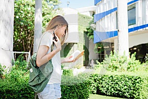 Asian woman tourist backpacker smiling and using smartphone traveling alone holidays outdoors on city street.