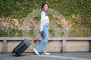 Asian woman tourist is going to holiday trip while looking with smiling at the camera and walking