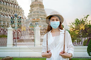 Asian woman tourist with mask is traveling at Wat Arun in Bangkok, Thailand