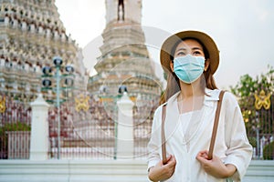 Asian woman tourist with mask is traveling at Wat Arun in Bangkok, Thailand