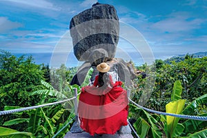 Asian woman tourist in red dress sightseeing and enjoying the view of overlap stone at Koh Samui in Thailand