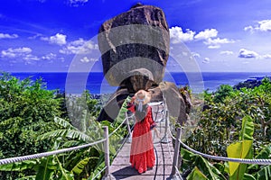 Asian woman tourist in red dress sightseeing and enjoying the view of overlap stone at Koh Samui in Thailand