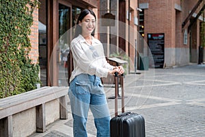 Asian woman tourist standing with smiling and holding black luggage to preparing on holiday trip