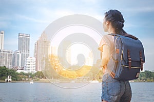 Asian woman tourist traveller backpack watching the beauty of the cityscape. at the scenic spot with a pond. at Bangkok Thailand