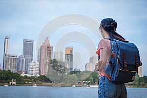 Asian woman tourist traveller backpack watching the beauty of the cityscape. at the scenic spot with a pond. at Bangkok Thailand