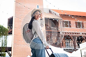 Asian woman tourists are traveling on holiday trip with hat and holding luggage