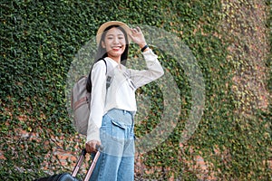 Asian woman tourists are traveling on holiday trip with hat and holding luggage