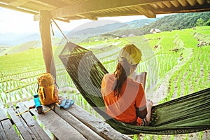 Asian woman travel nature. Relax read a book in the hammock. the balcony of the resort. View of the field on the Moutain in summer