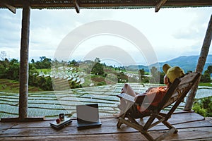 Asian woman travel nature. Relax read a book in the hammock. the balcony of the resort. View of the field on the Moutain in summer