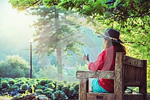 Asian woman travel nature. Travel relax. Read the book on the bench in the park in summer