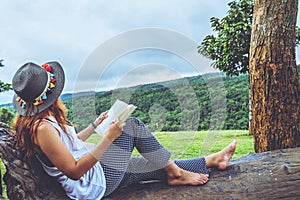 Asian woman travel nature. Travel relax. Study read a book. Nature Education. At public park in summer