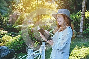 Asian woman travel nature. Travel relax. Study read a book. Nature Education Write a note At public park in summer. In Thailand