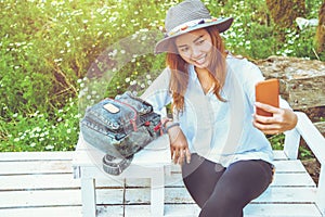 Asian woman travel nature. Travel relax. taking photos Selfie  on the bench in the park in summer