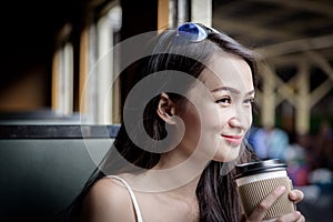 Asian woman traveler has drinking coffee in the train with happiness at Hua Lamphong station at Bangkok, Thailand.