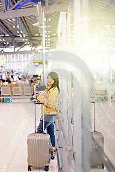 Asian woman traveler using mobile phone in airport,Lifestyle using cell phone connection concept,Feeling happy and smiling