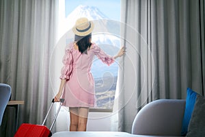 Asian woman traveller arrive to room in hotel and open curtain for enjoy fuji view photo