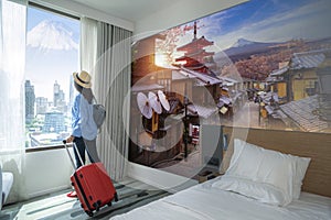 Asian woman traveller arrive to room in hotel and open curtain for enjoy fuji view photo
