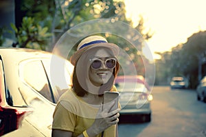 Asian woman by traveller lifestyle with smartphone in hand toothy smiling face relaxing emotion in citylife