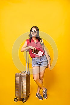 Asian woman traveller with suitcase in studio.