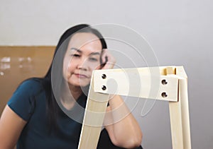 Asian woman  try to assemble knock down furniture and getting confused photo