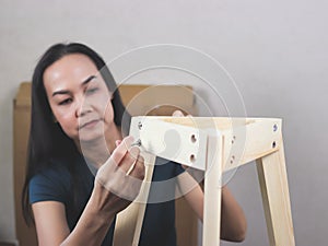 Asian woman  trying to assemble knockdown furniture, screwing the screw into wood. selective focus