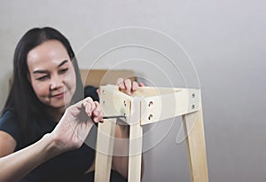 Asian woman  trying to assemble knockdown furniture, screwing the screw into wood. selective focus