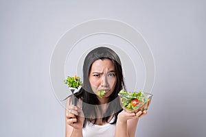 Asian woman trying to eat salad for diet isolated over white background