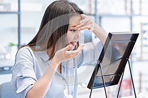 Asian woman trying to put contact lenses into her eyes