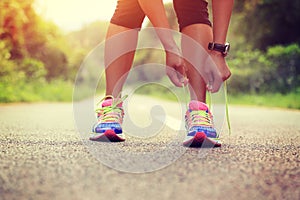 Asian woman tying shoelace on fossil forest trail