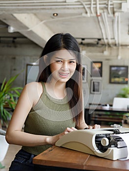 Asian woman with typewriter in a cafe.