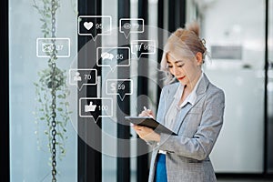 Asian woman typing smartphone, keyboard with laptop computer of Social media and Marketing virtual icons screen concept