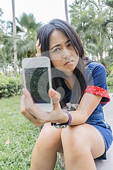 Asian woman unhappily at broken smart phone.