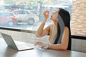 Asian woman unpacking ATK self test and insert nasal swab following the procedure from internet computer laptop