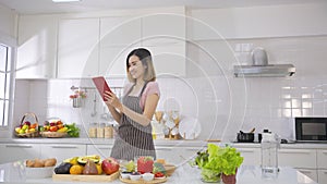 Asian woman use finger slide on tablet screen prepare ingredients for cooking follow cooking online video clip