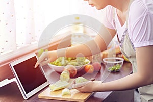 Asian woman use finger slide on tablet screen prepare ingredients for cooking follow cooking online video clip on website.