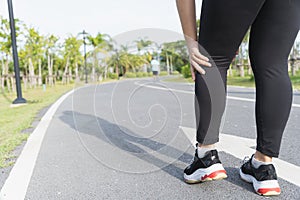 Asian woman use hands hold on her knee injury while running on road in the park, Injury from workout concept