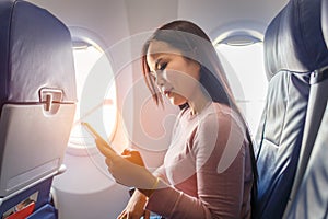 Asian woman use of mobile phone inside airplane