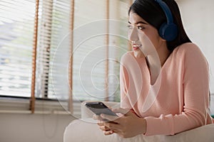 Asian woman uses her smartphone. uses headphones to listen to music Enjoying a song or listening to a meditation audio course