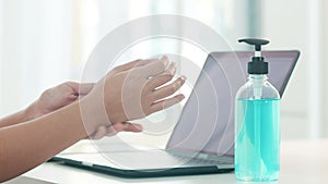 Asian woman using alcohol gel hand sanitizer wash hand before open laptop for protect coronavirus. Female push alcohol to clean
