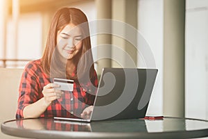 Asian woman using credit card shopping online in coffee shop vintage color tone.