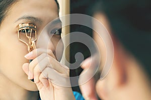 Asian woman is using eyelash curler.