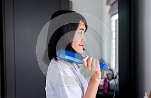 Asian woman using hair irons with straightening