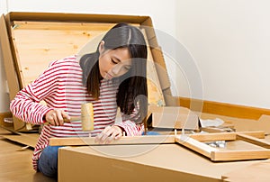 Asian woman using hammer for furniture assembling