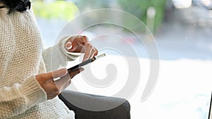 An Asian woman using her smartphone while relaxing in the cafe. side view and close-up image