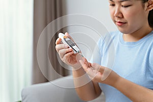 Asian woman using lancet on finger for checking blood sugar level by Glucose meter, diabetes photo